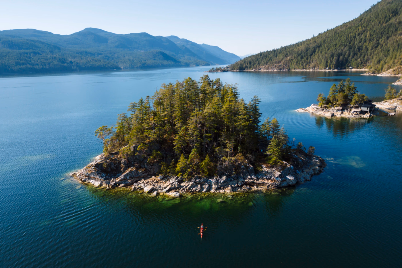 Red kayak sits in front of a tree covered island