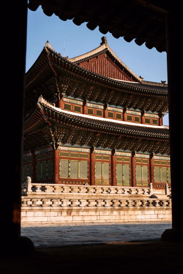 A large ornate temple is framed by two large pillar at Gyeongbokgung Palace, South Korea