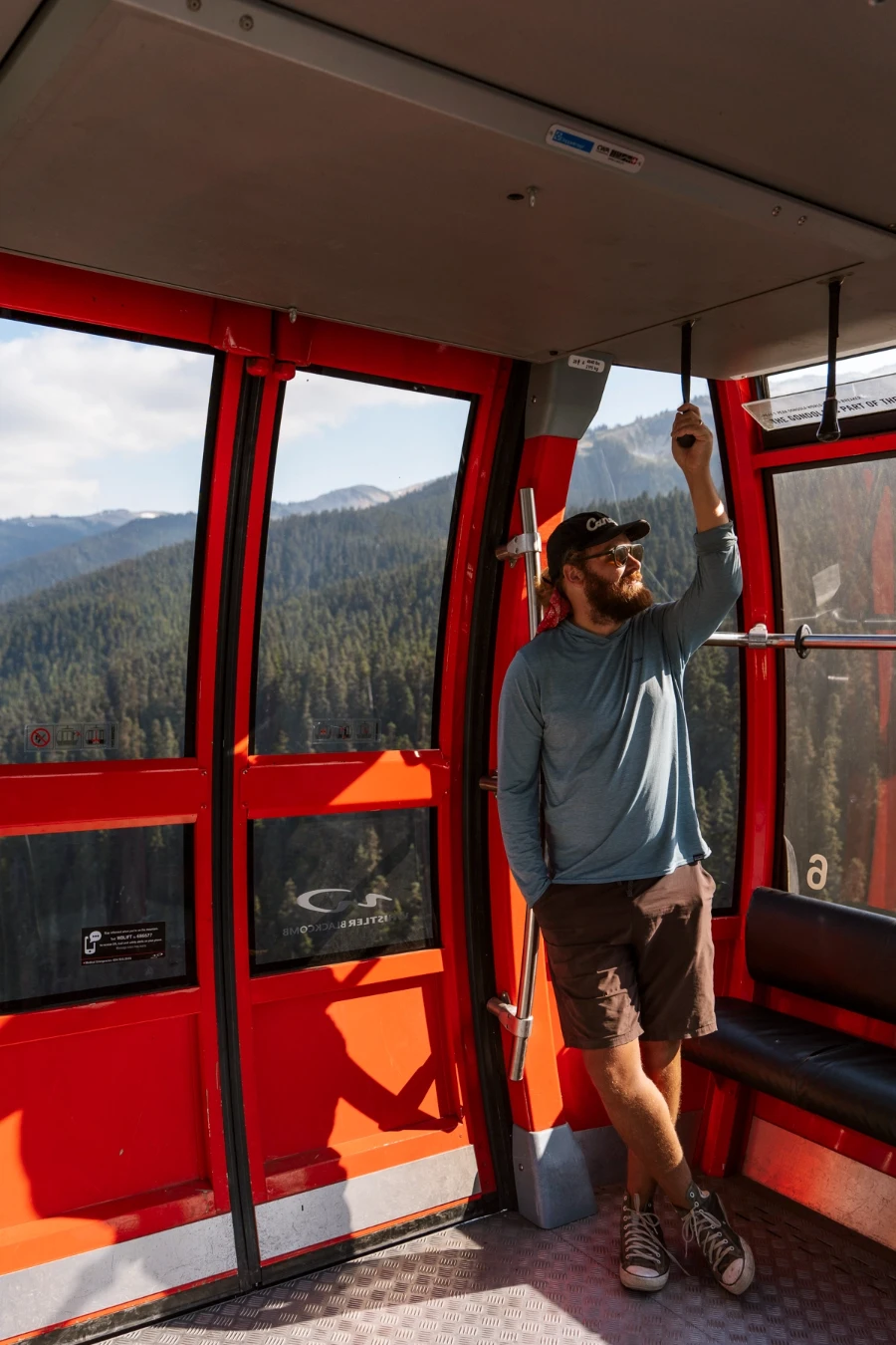 Man standing in a large red gondola traversing the Peak 2 Peak ride between Whistler and Blackcomb Mountain