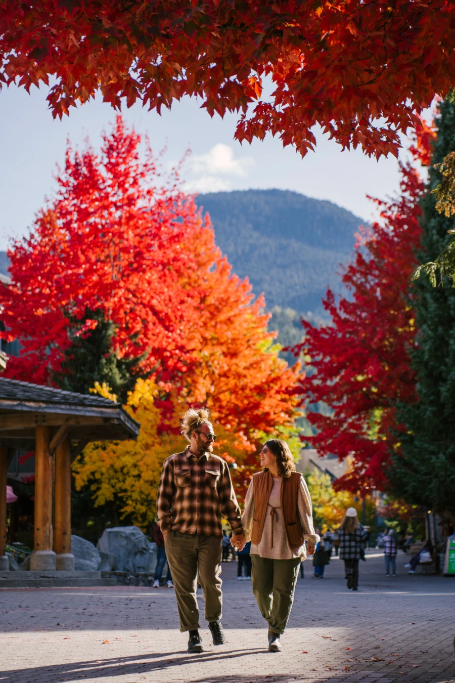 A man and woman walk hand in hand through the cobble stone pedestrian street of Whistler village