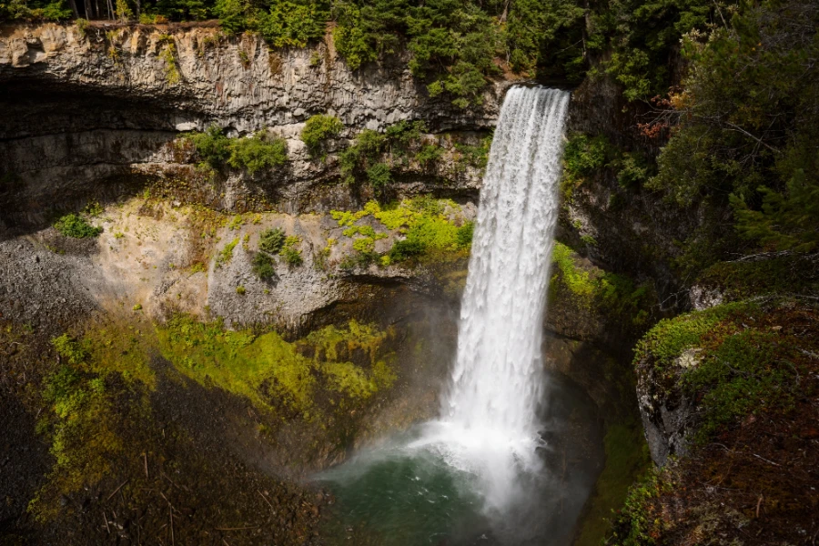 A torrent of water pours over a cliffs edge into a volcanic canyon at Brandywine Falls near Whistler