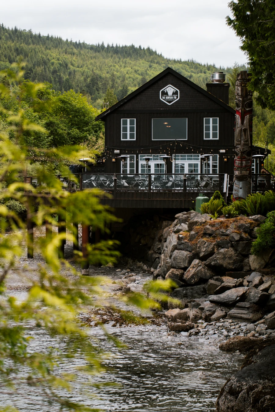 A large wooden pub on the shore at low tide in Port Renfrew