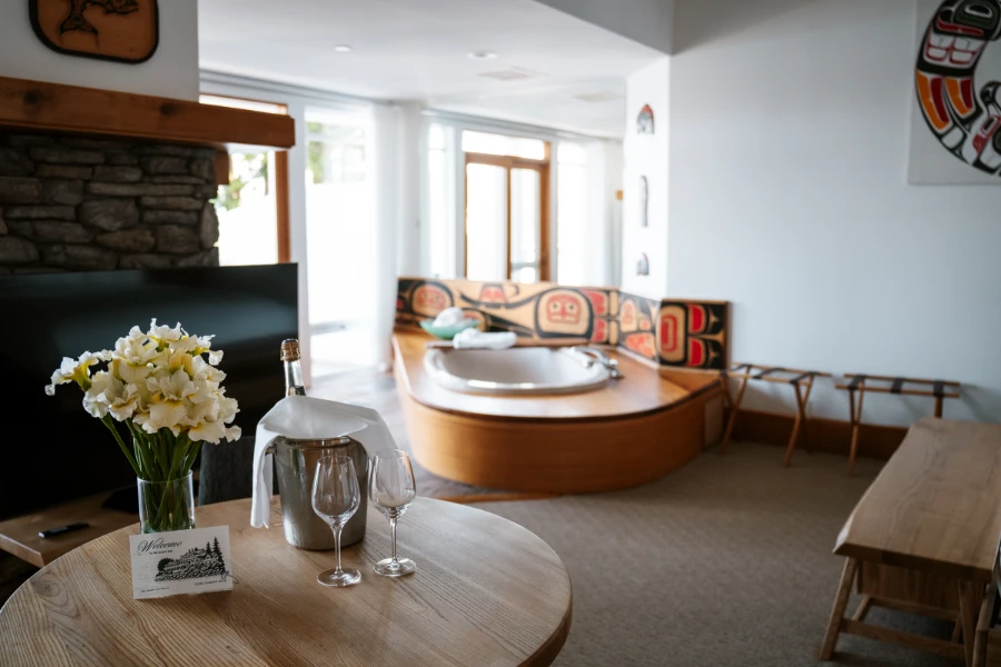 A hotel room with a large luxurious tub and a bottle of wine in a bucket of ice sitting on a table at the Sooke Harbour House