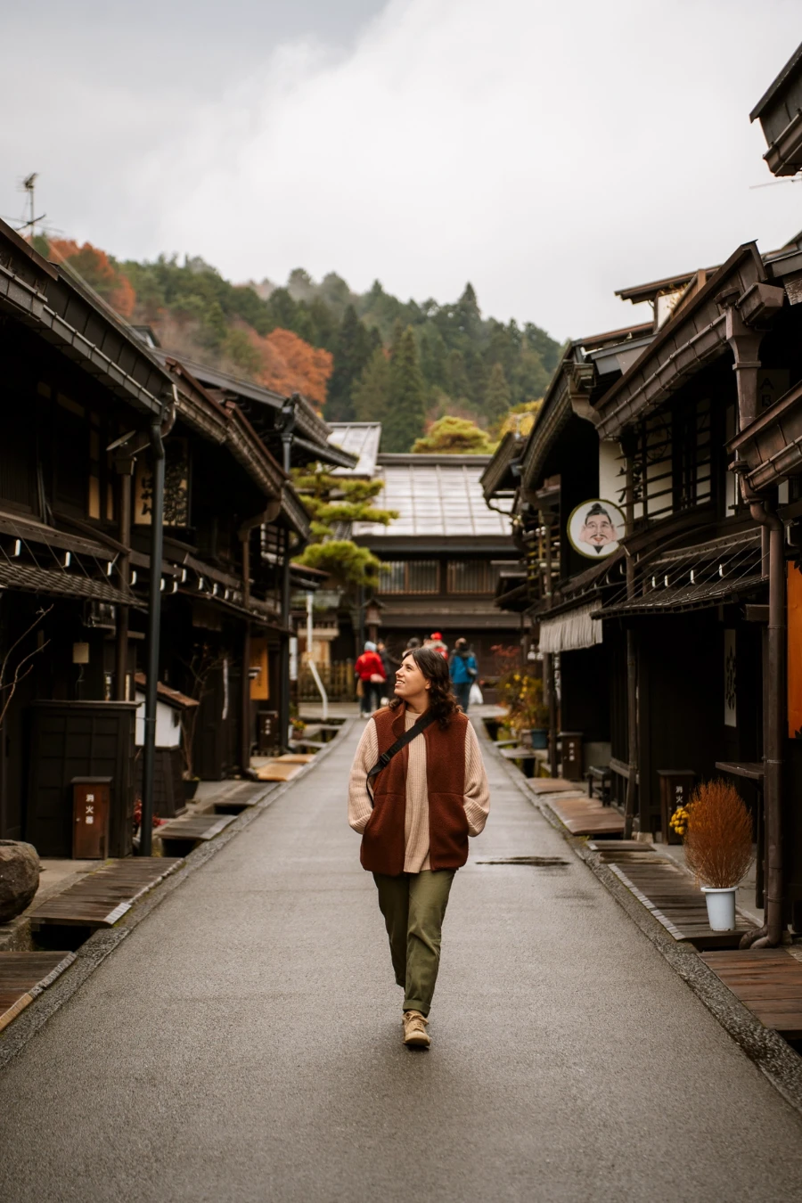 A woman walks down an empty street lined by wooden storefronts in Sanmachi Suji (Old Town)