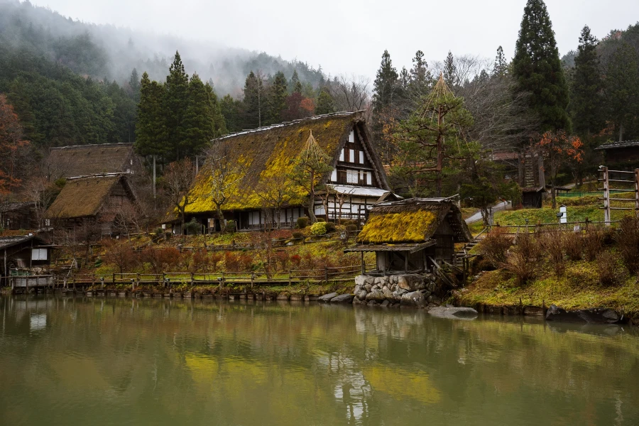 A pond at Hida Folk Village reflects a thatched roof mill