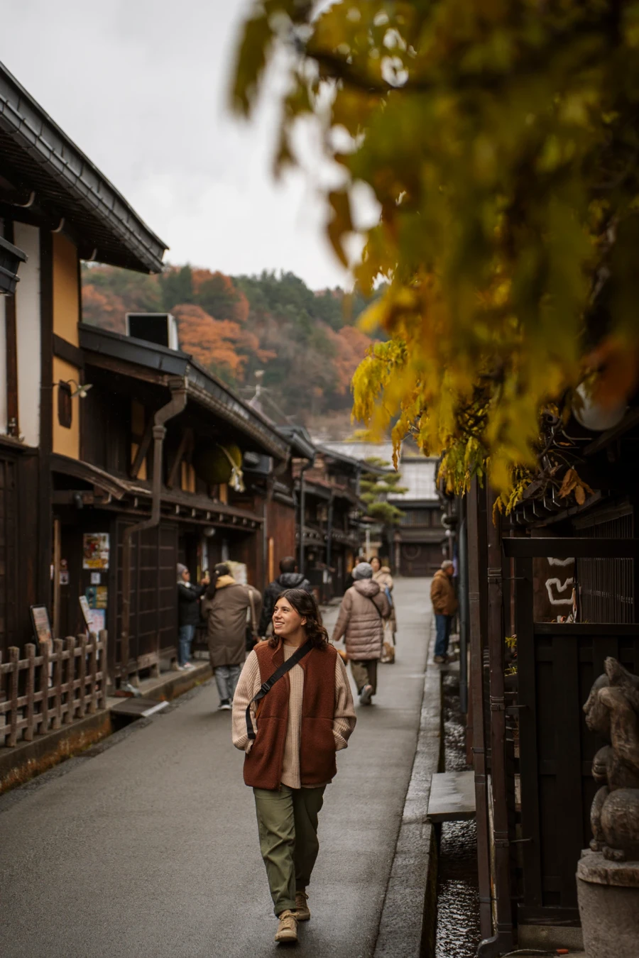 A woman walks down the old town streets of Takayama with a crowd of tourists shopping behind her