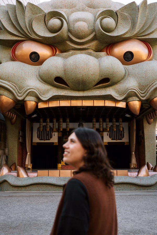 A woman standing in front of a large statue of a dragon with its mouth open