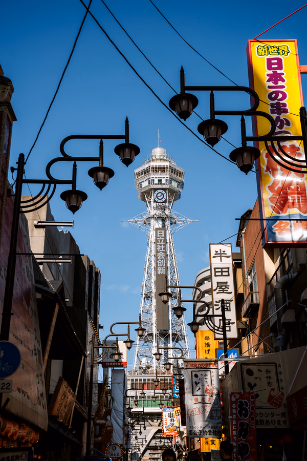 A large metal communications tower stands at the end of a street that is covered with roadside signs