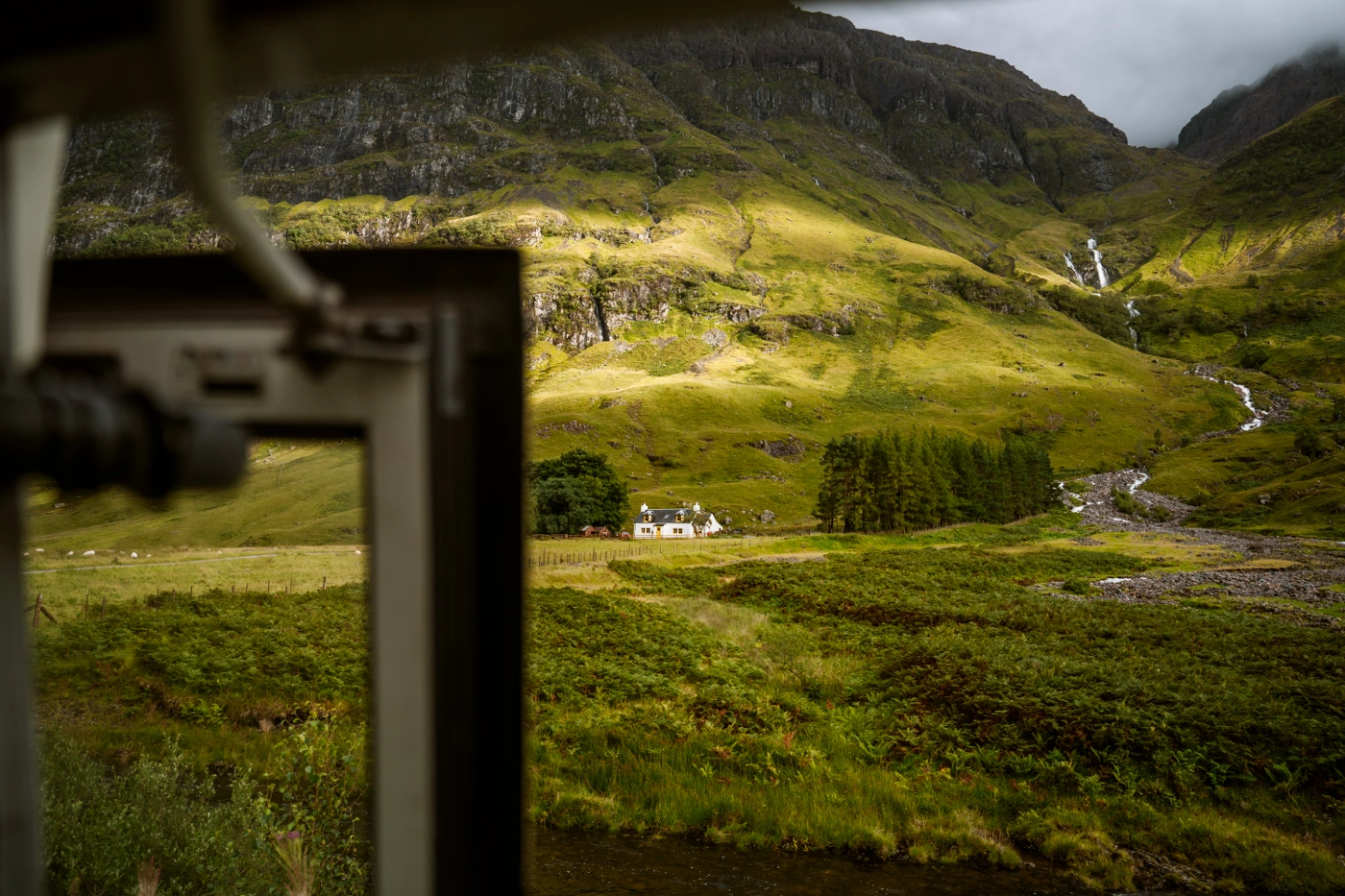 The clouds cast shadows and spot light on rolling green hills in the Scottish Highlands near Glencoe