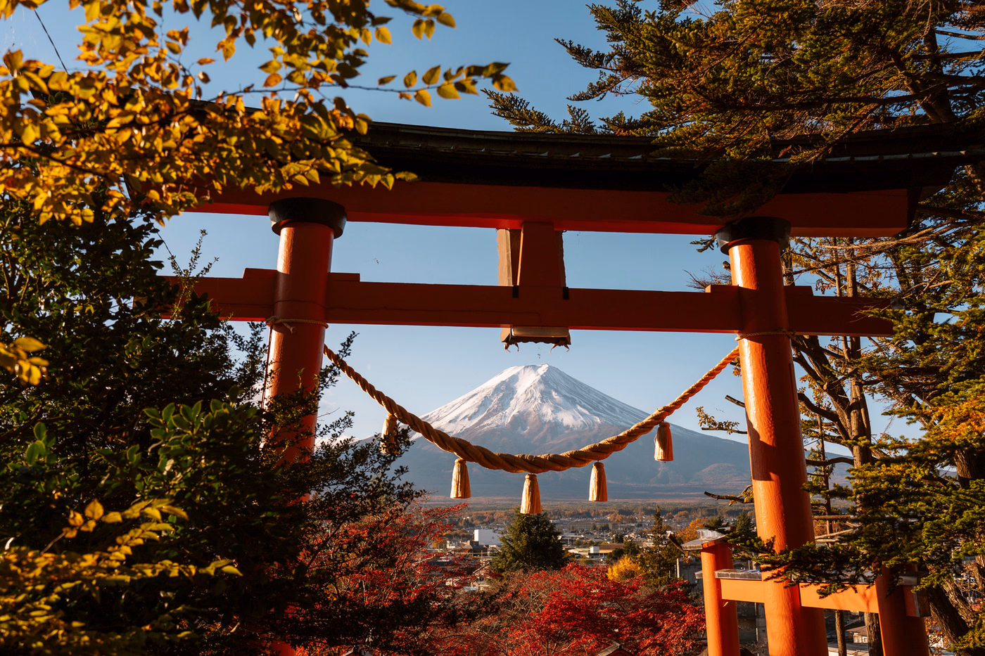 A large red Tori gate sits atop a hill framing Mt. Fuji in the distance