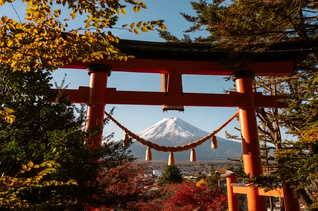 A large red Tori gate sits atop a hill framing Mt. Fuji in the distance
