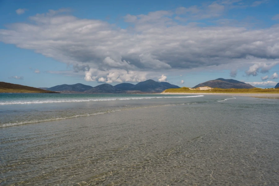 Long calm waves pass over the shallow and glistening waters of Seilebost Beach, Isle of Harris