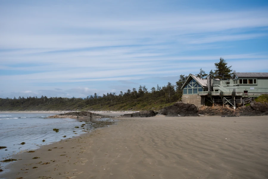 A wide flat sandy beach with a large building built on stilts in the distance