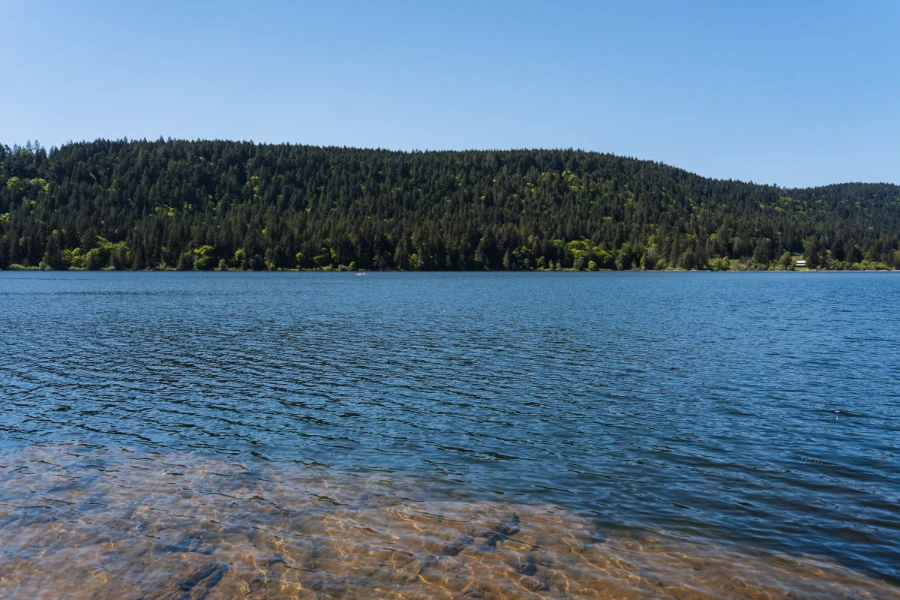 A rocky slab is covered by a few inches of water before giving way to deeper water surrounded by forested hills on every side