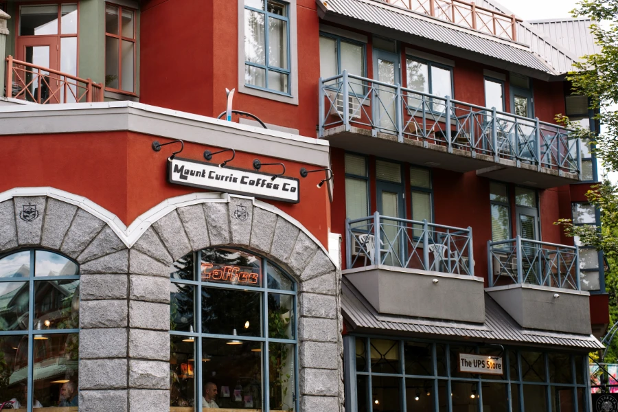 A large white sign above a stone arch reads ‘Mount Currie Coffee Co.’ and a red lit neon sign inside the window below the arch reads ‘Coffee’