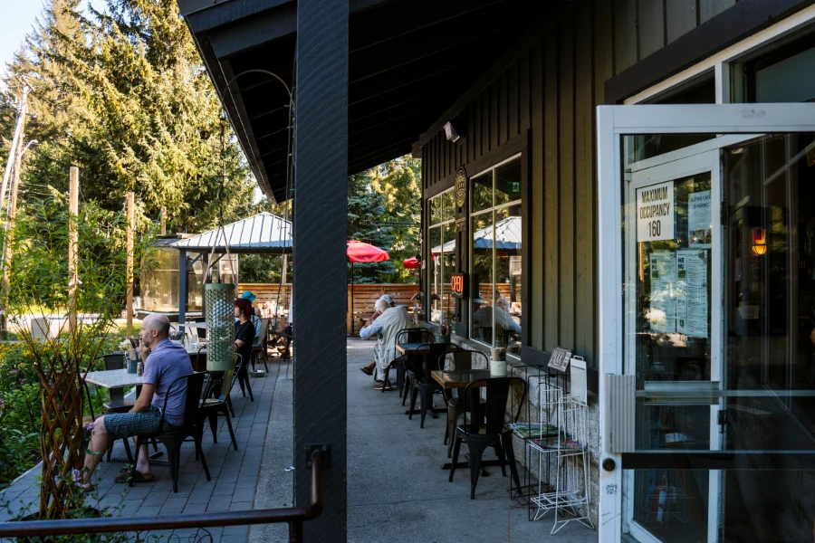 Several groups of people sitting outside the Alpine Cafe near Whistler on the patio.