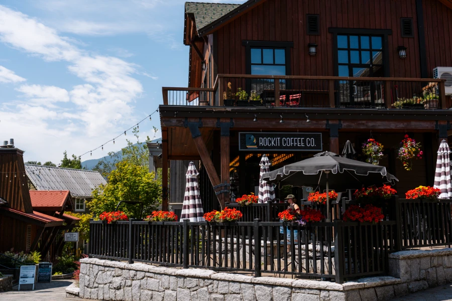 Two stories of patio seating with beautiful red flowers scattered around at Rockit Coffee Co. in Creekside