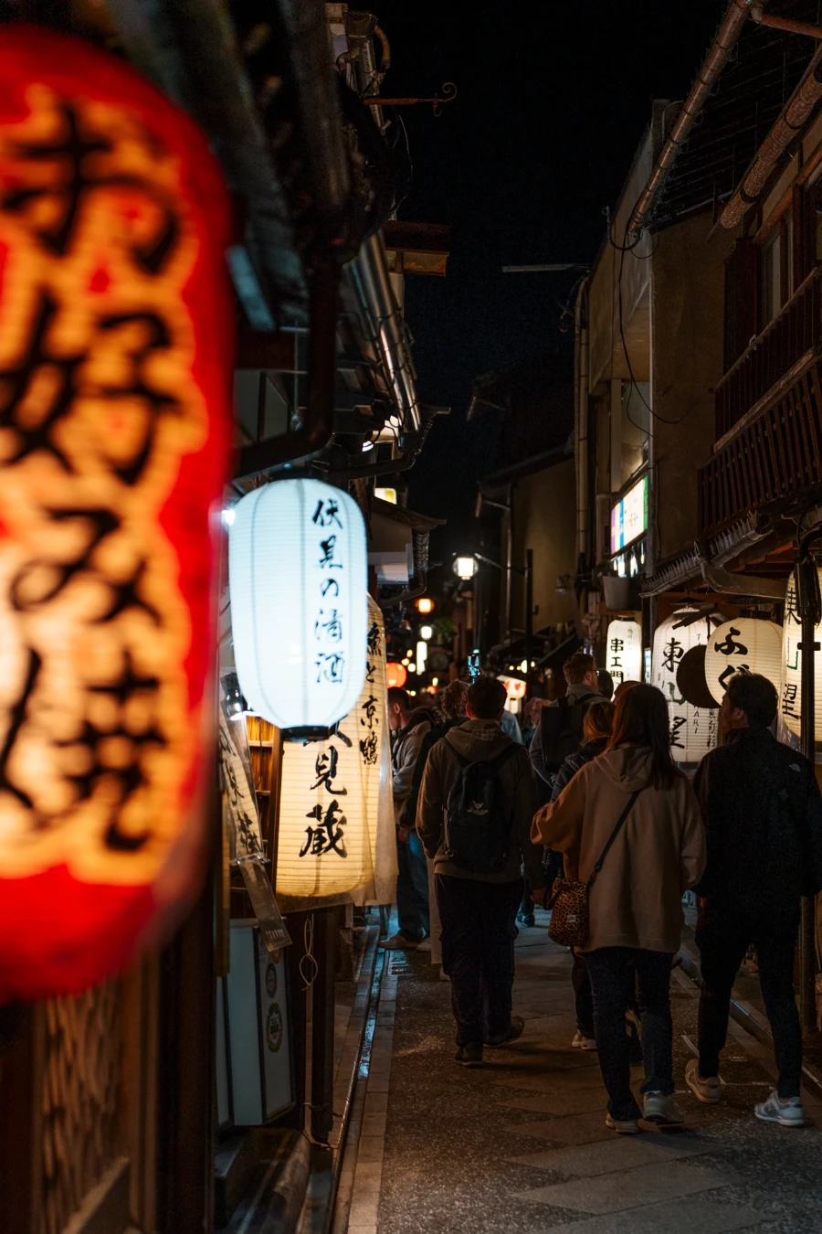 A crowd of tourist walk along the lantern lined street in Pontocho District, Kyoto