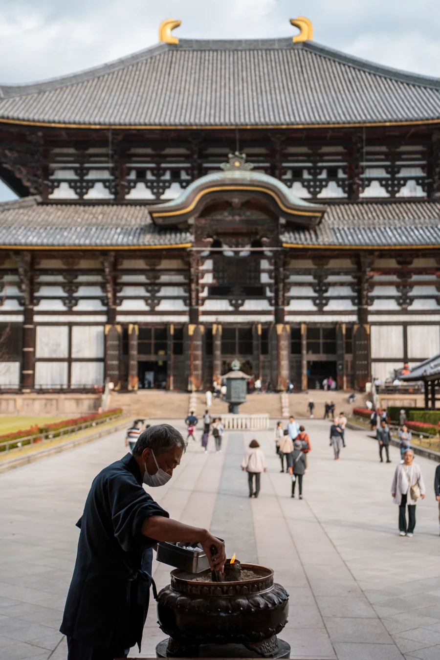 A man lights incense in front of Todai-ji temple Nara Park, Japan