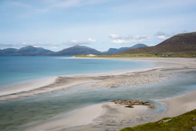 Rolling hills in the distance and white sand exposed by a low tide on a ideal beach on the Isle of Lewis and Harris