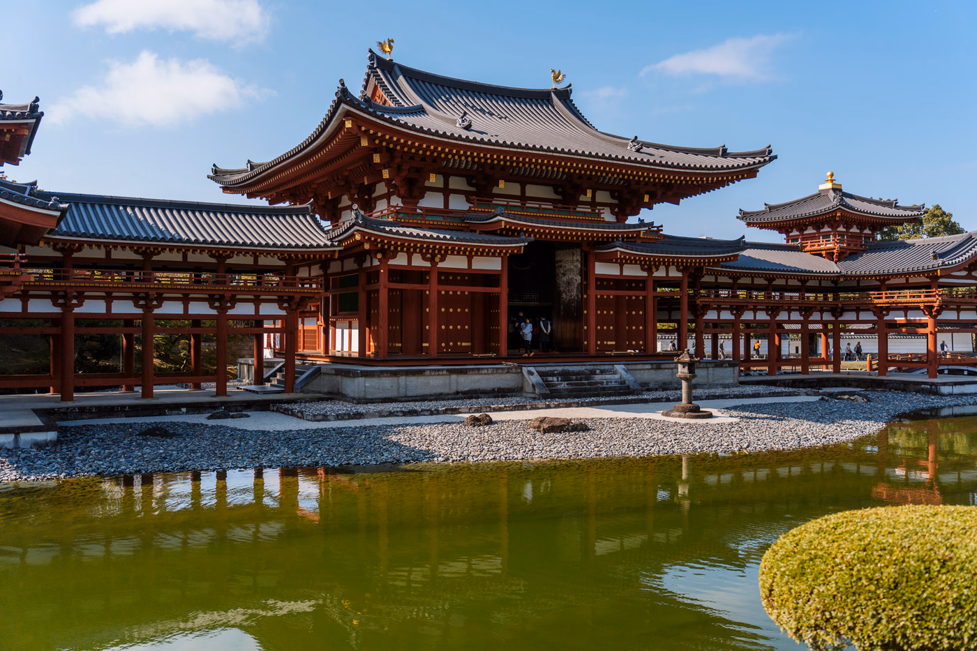 A large traditional Japanese Temple is reflected in an adjacent pond