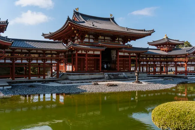 A large traditional Japanese Temple is reflected in an adjacent pond