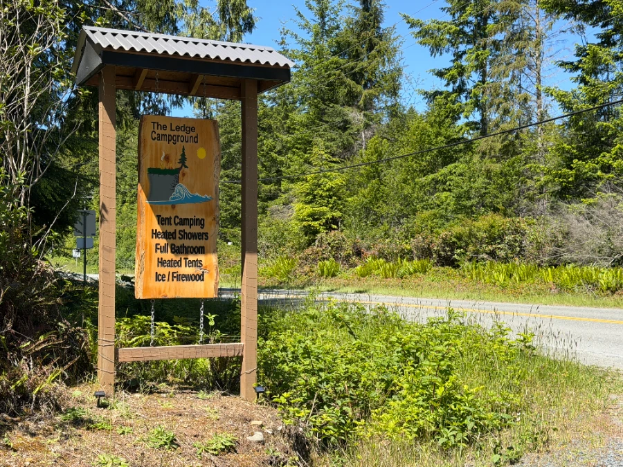 A wooden sign advertises The Ledge Campground and its heated showers, full bathroom, and ice and firewood for sale