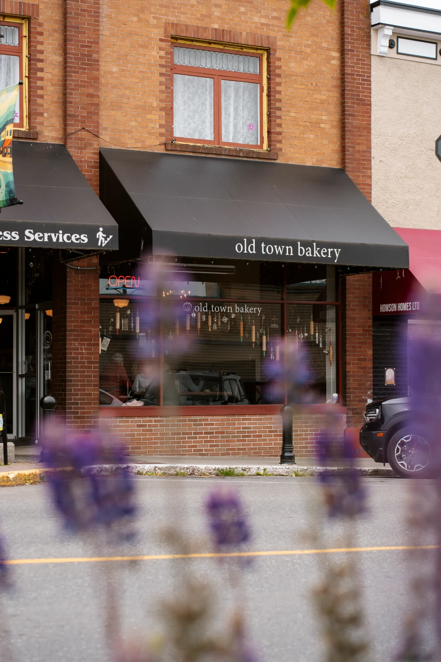 A black awning on a building across the street with white letters written on it reading ‘Old Town Bakery.’