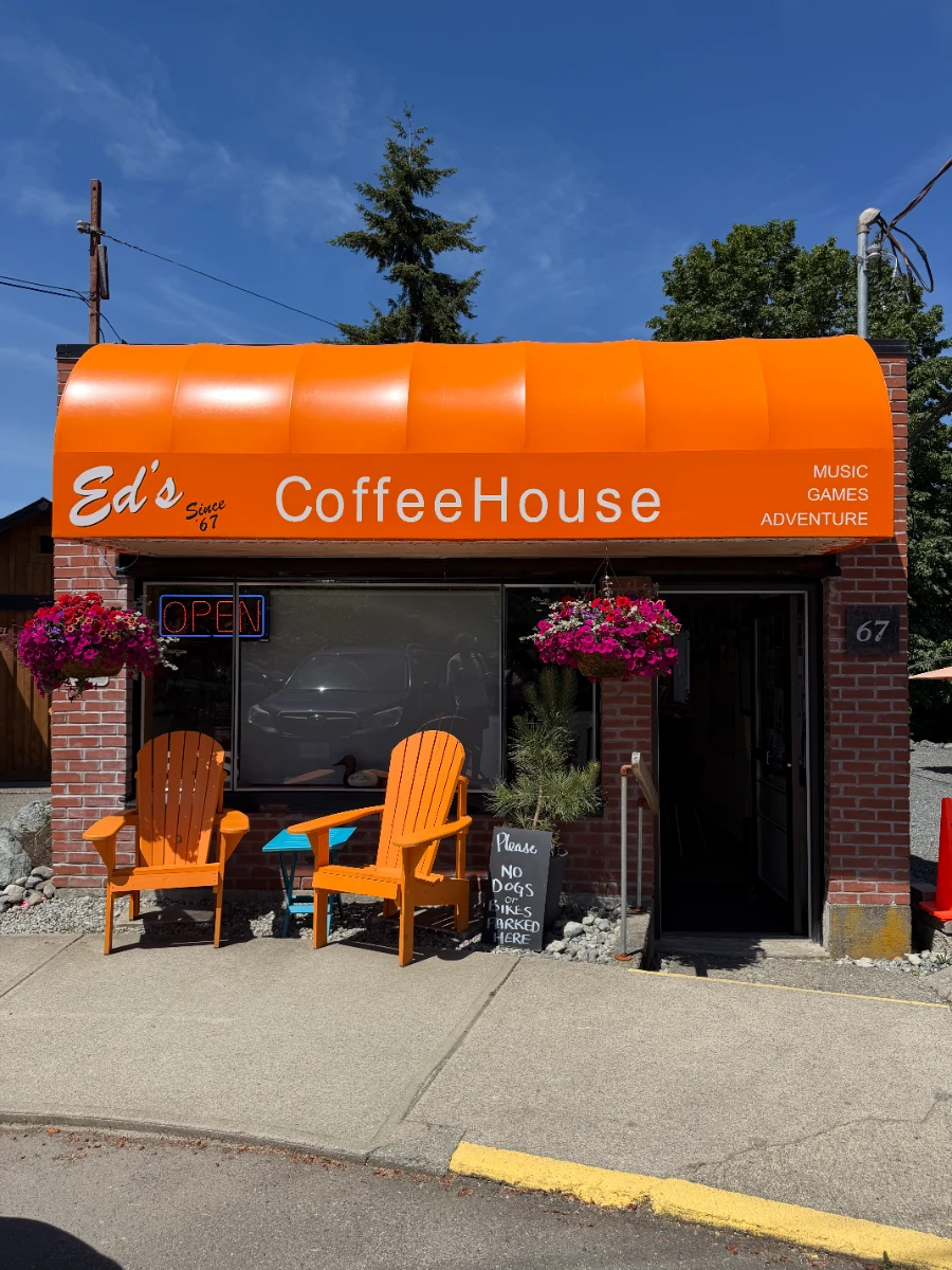 A small coffee house with a bright orange awning that reads Ed’s Coffee House