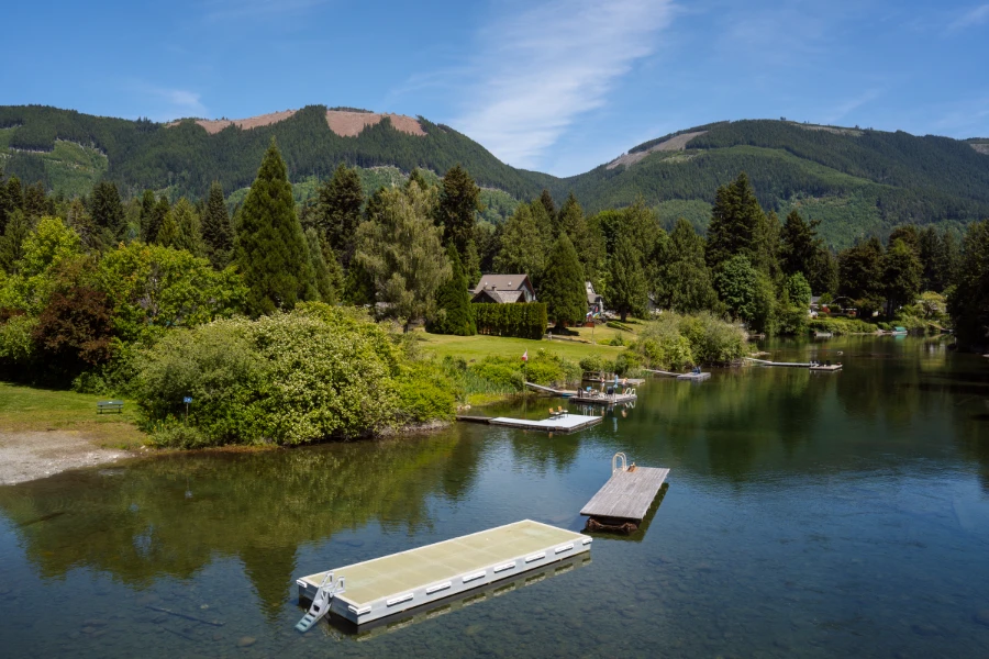 Two floating docks floating on shallow water with a lush shore behind dottted by docks and cottages