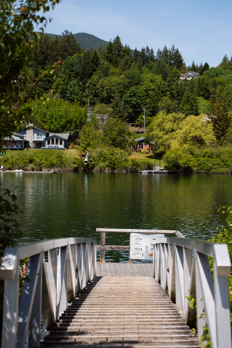 A wooden dock floating on Cowichan Lake at the end of a ramp with large metal railings