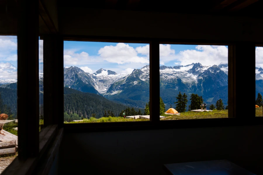 Wooden tent platforms on the mountainside seen through the windows of the day shelter at Elfin Lakes in Squamish