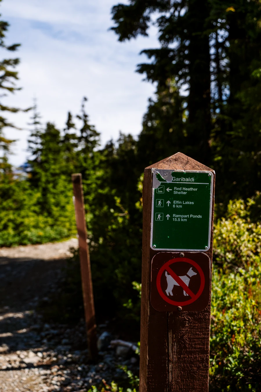 A signpost on the side of the trail up to Elfin Lakes in Squamish shows the directions and distances to the Red Heather Shelter, Elfin Lakes, and Rampart Ponds