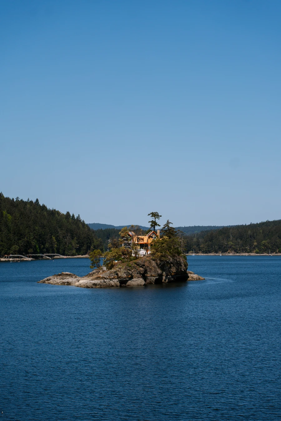 A large cottage on a rocky pillar that is surrounded by water on all sides