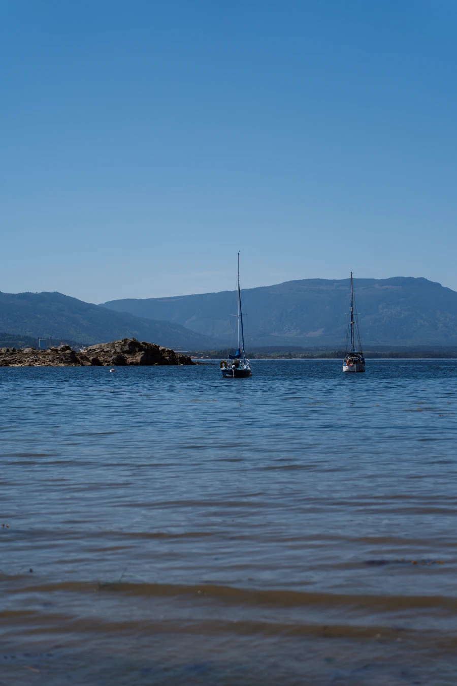 Two sailboats anchored in the calm waters of Vesuvius Bay, Salt Spring Island