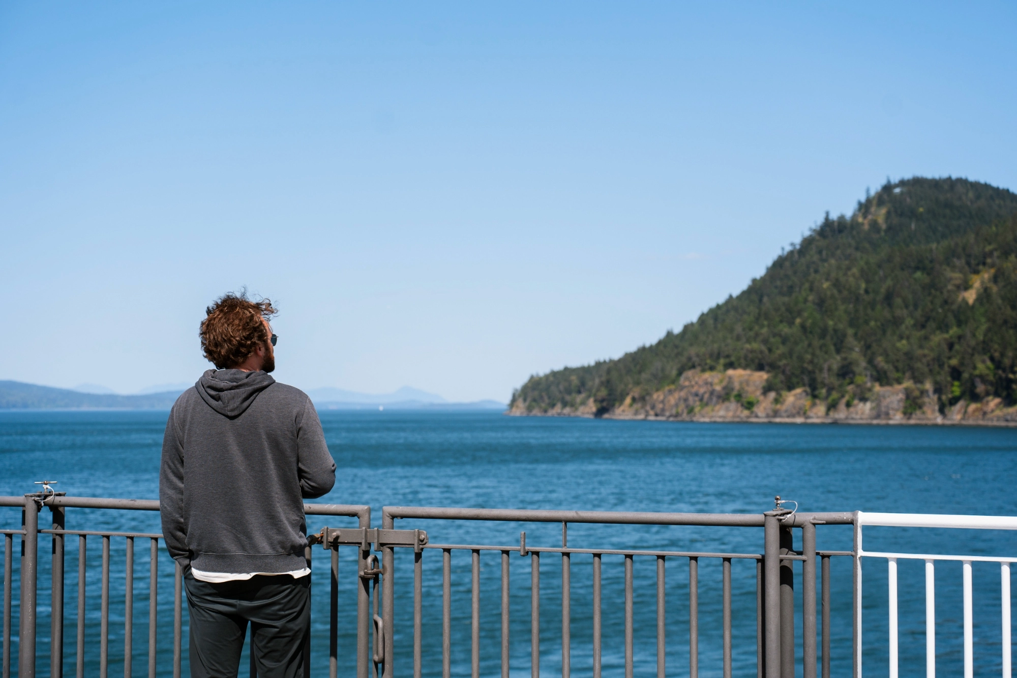 A man stands on the deck of a  BC ferries as it passes several Gulf Islands.