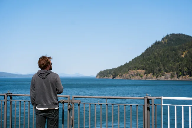 A man stands on the deck of a  BC ferries as it passes several Gulf Islands.