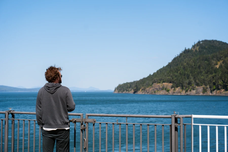 A man stands next to the railing of a BC ferries looking out to the Gulf Islands