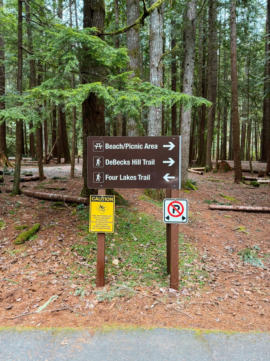 A sign post amongst an evergreen forest point towards several trials and picnic areas