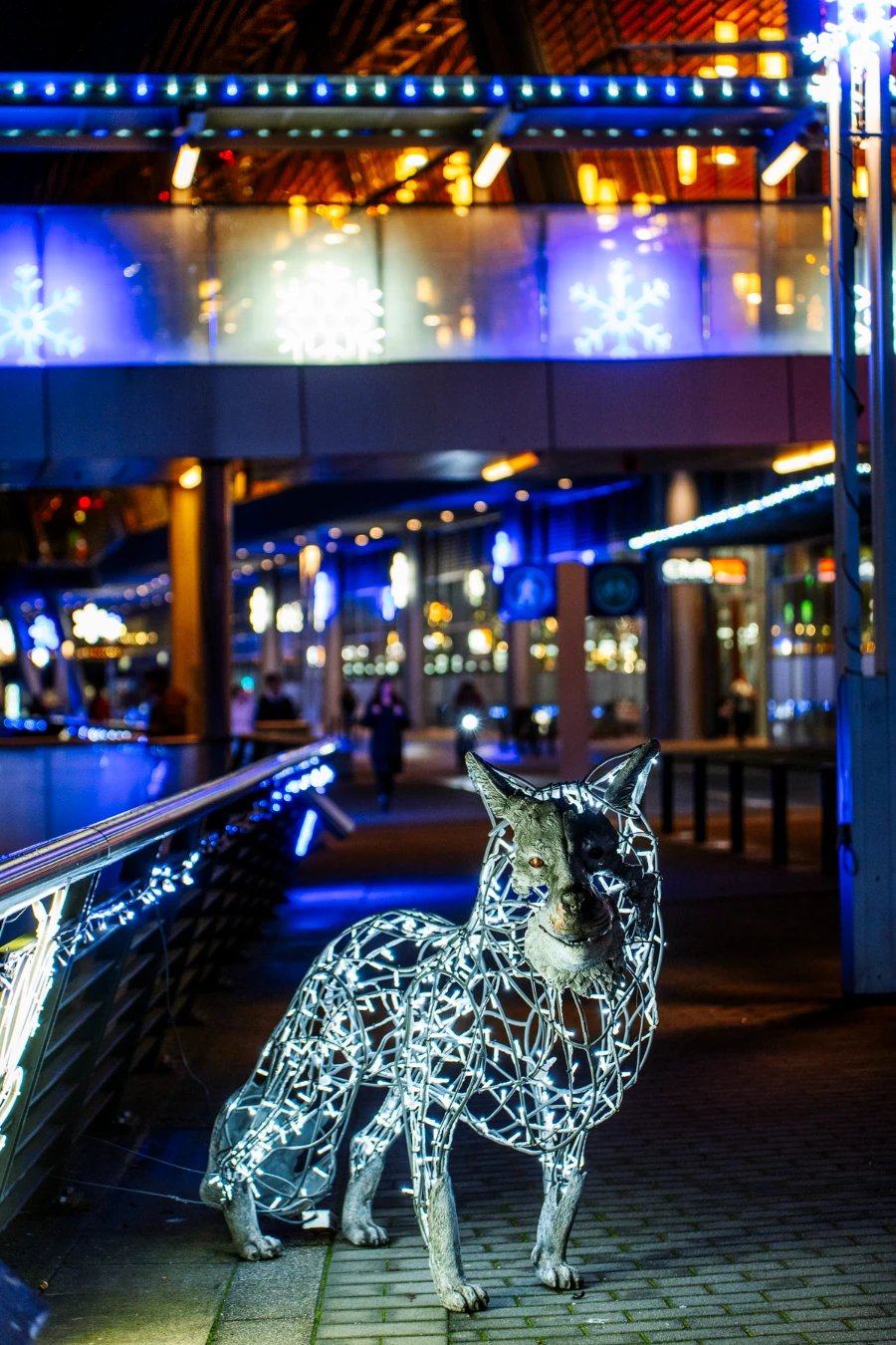A string light display statue of a wolf stands along the walkway of Coal Harbour