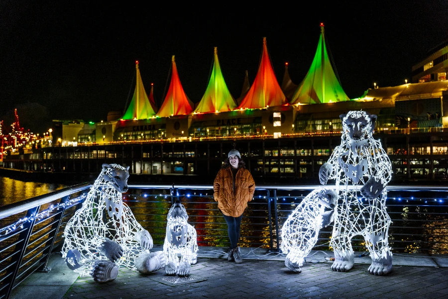 A woman stands next to string light statues of polar bears