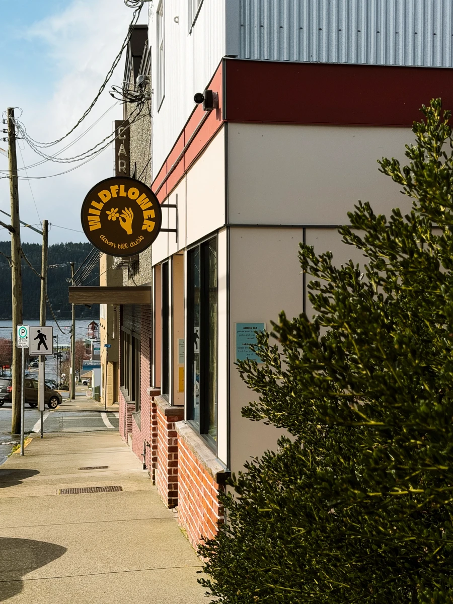 The facade of a cafe with a sign hanging above the sidewalk that reads 'Wildflower Cafe'
