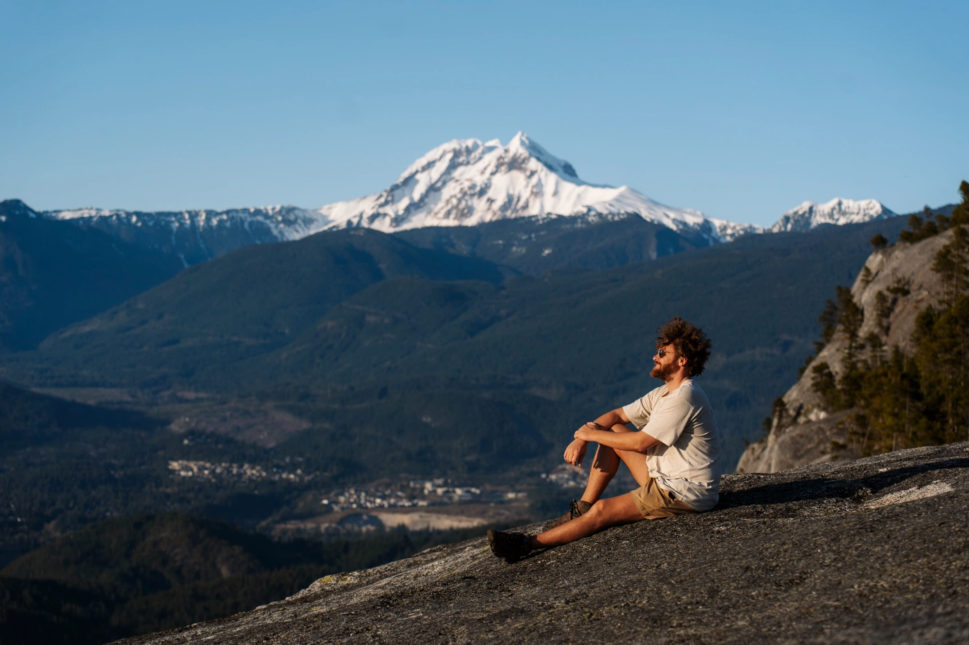  A man sitting on the bare granite cliff at first peak on Stawamus Chief