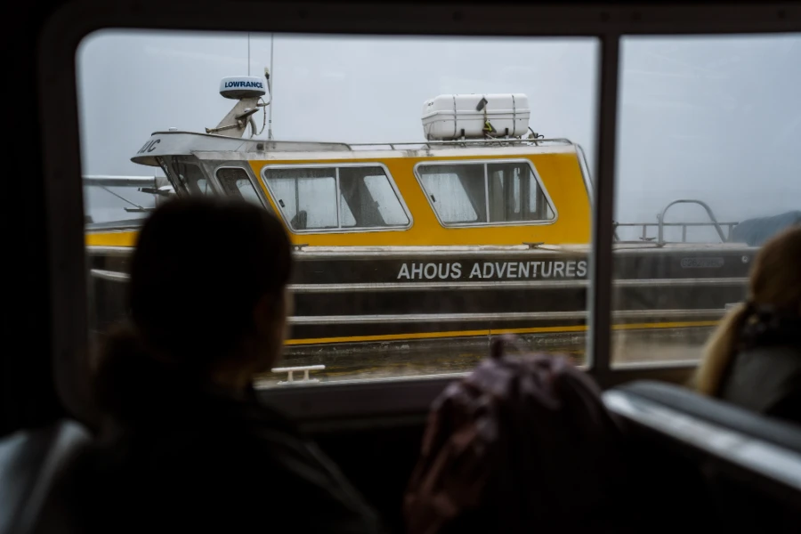 A boat with a clear label reading Ahous Adventures is framed through the window of another boat