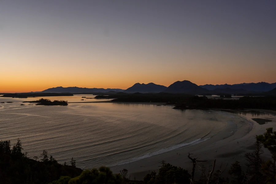 Rows of gentle waves roll into Cox Bay at sunset