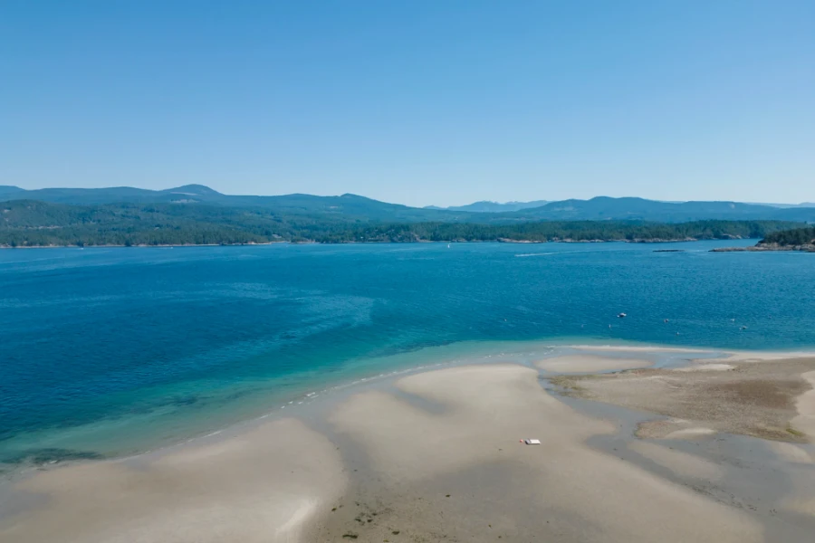 Massive sandy beach exposed by a receding tide with the Sunshine Coast on the horizon