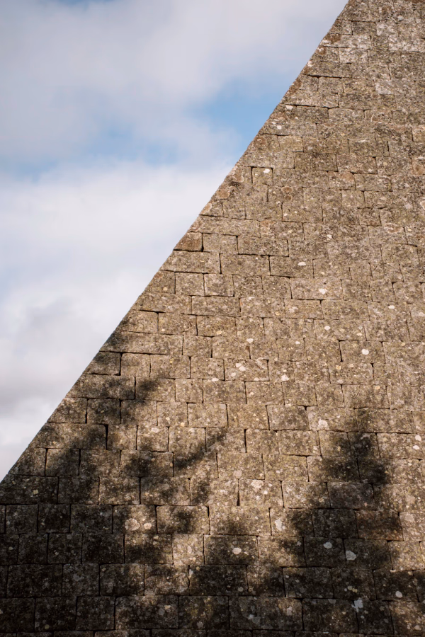 Trees casting a shadow on a large stone pyramid
