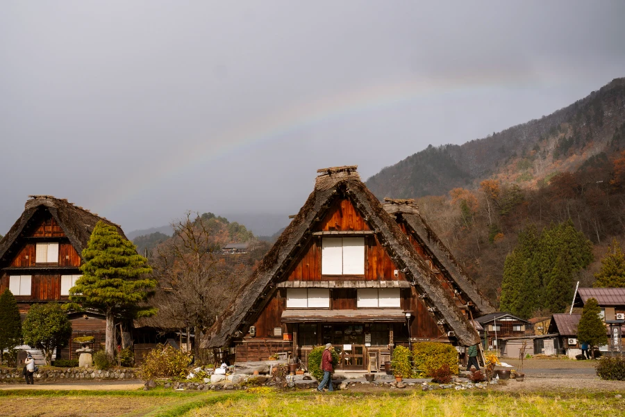 A rainbow streaks across the sky above a traditional thatch roof Japanese House
