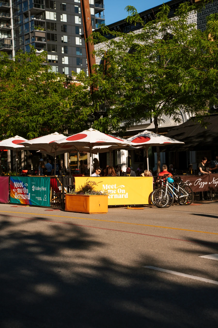 Several white umbrellas cast shade over a busy patio on Bernard Street in Kelowna