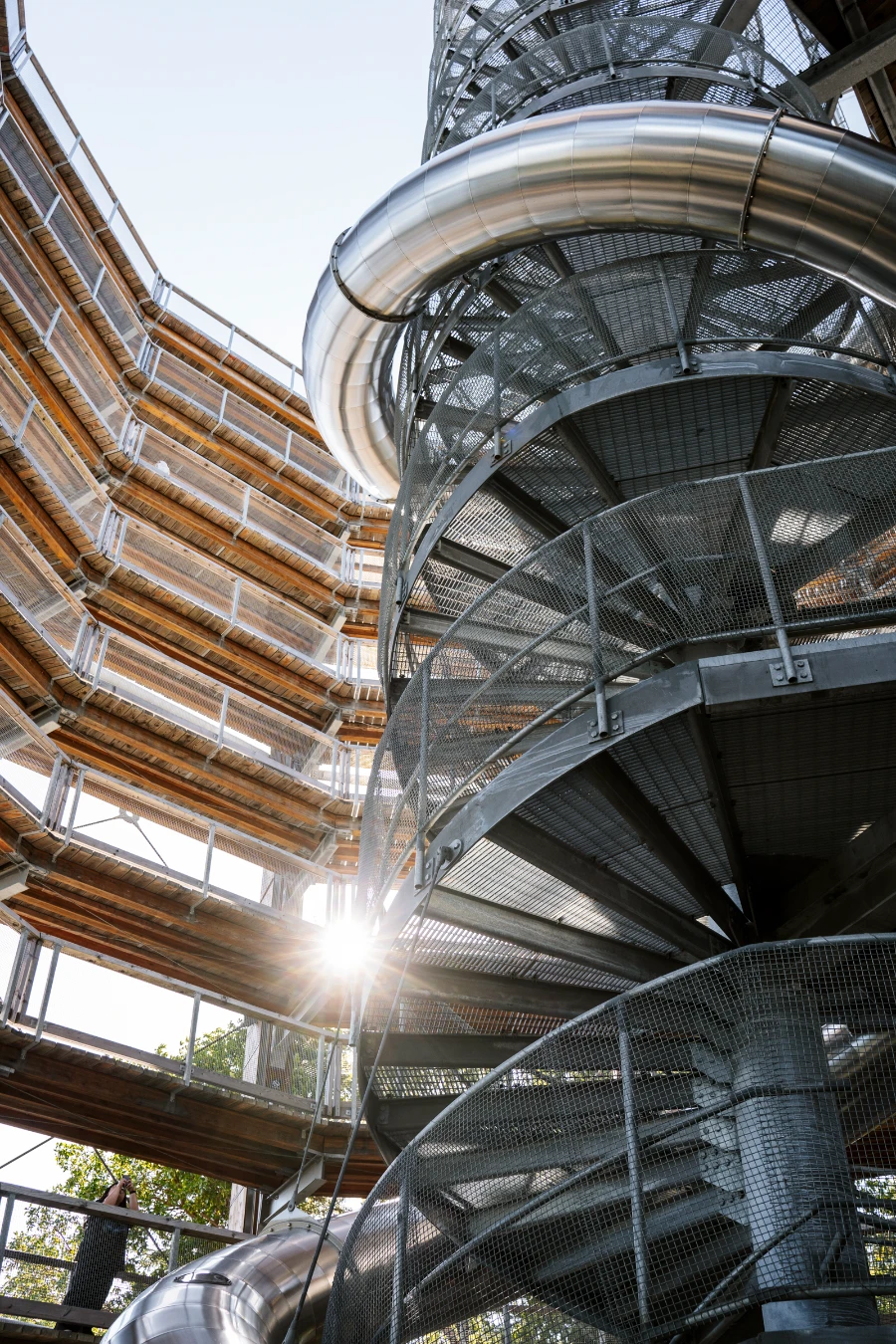 Sunflare shines through the levels of the sloped walkway of the Malahat Skywalk and the spiral metal staircase at its center